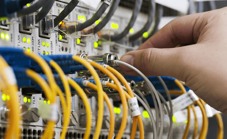 Technician connecting a fibre optic cable to an active network switch